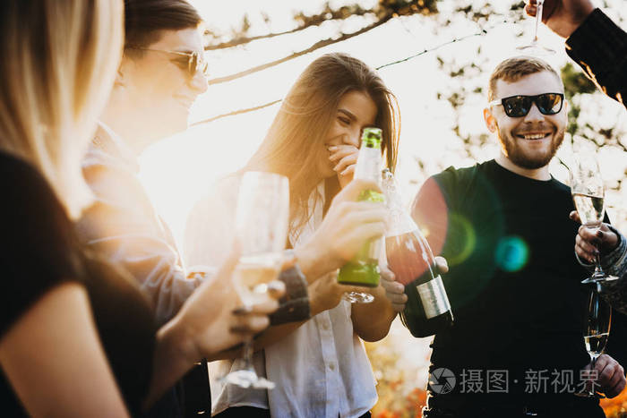 年轻的男人和女人在阳光明媚的日子里在大自然中欢笑和饮酒