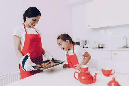 妈妈和女儿的围裙。 为所有家庭烤一块饼干。 快乐幸福的家庭一起烤蛋糕。 孩子和妈妈一起烤蛋糕。 快乐的妈妈和厨房里快乐的女儿。 