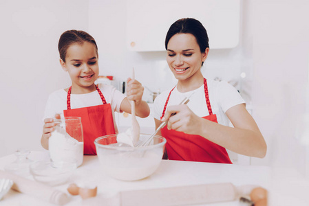 面粉做面团。 准备烤箱饼干蛋糕派松饼煎饼。 快乐的女孩用围裙帮助美丽的母亲。 和妈妈一起在厨房做饭。 乔伊孩子和妈妈做饭。 女厨