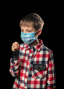 戴医疗面具的生病男孩在黑色背景下咳嗽