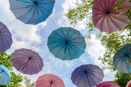 公园里有许多带有蓝天背景的多种颜色的雨伞。 夏季节日