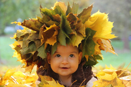 秋天。 戴着彩色叶子花环的女儿。