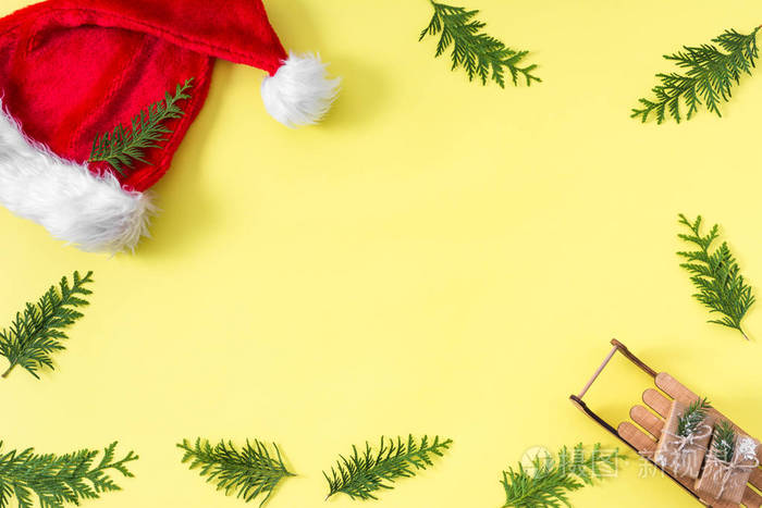 圣诞节背景与绿色圣诞树树枝装饰礼品盒黄色背景顶部视图复制空间文本。