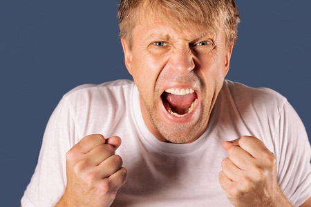 一个愤怒的男人在灰色背景下握着拳头的画像
