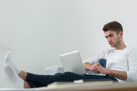一位年轻英俊面带微笑带着笔记本电脑在家工作的商人