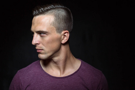 一个英俊的肌肉发达的白种人在演播室里拍摄僵硬的姿势和面部表情照片