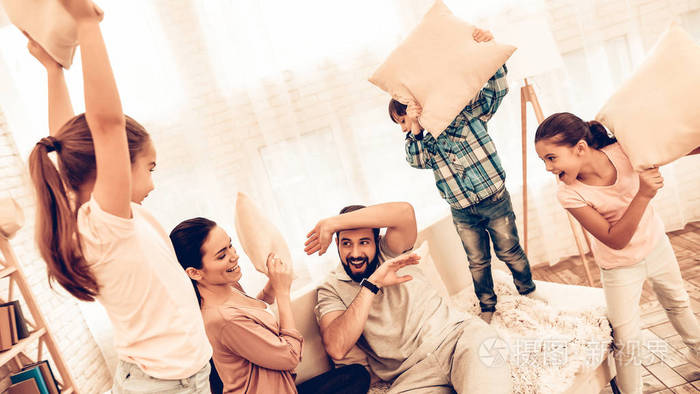 快乐可爱的大家庭有枕头打架. 孩子们和父母在家里的床上打枕头仗.