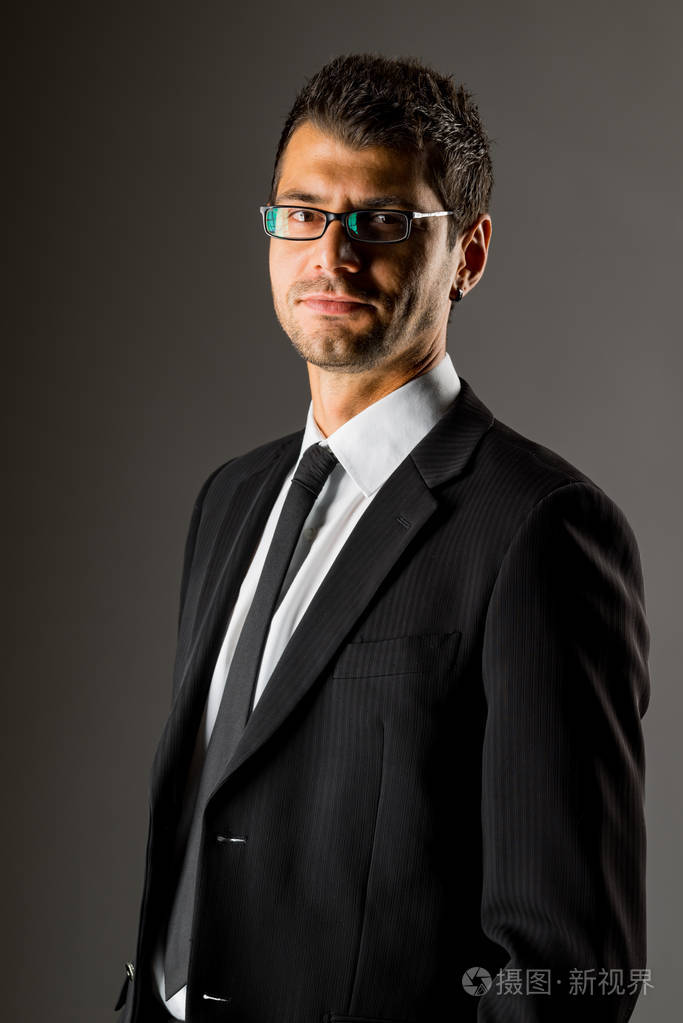 一个穿黑色西装的严肃男人.黑暗的背景.