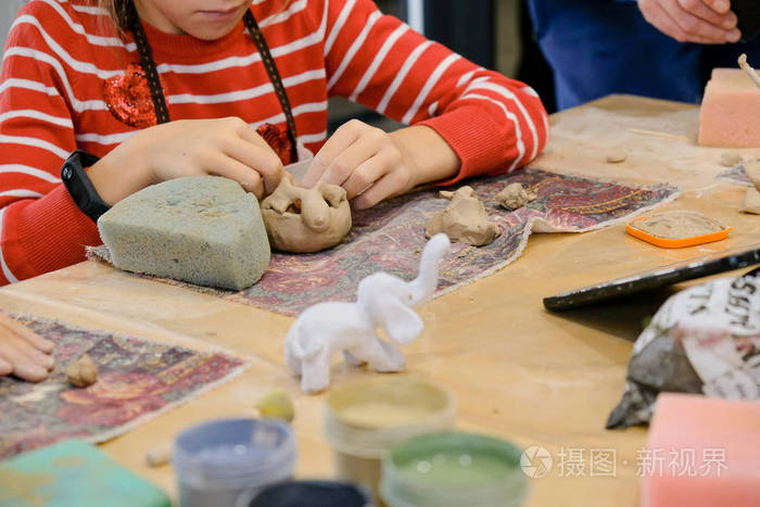一个孩子在造型课上用粘土塑造一个产品。
