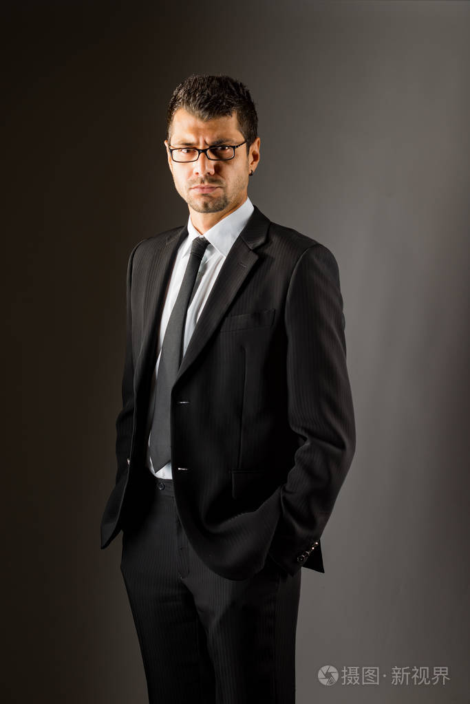 一个穿黑色西装的严肃男人.黑暗的背景.