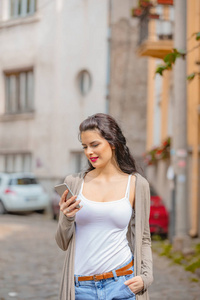 可爱的年轻女性在城市环境中使用手机。