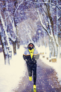 男人在下雪的公园和寒冷的天气慢跑。