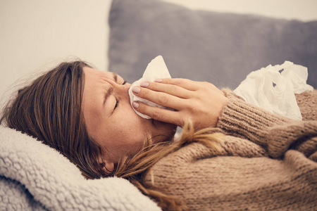 患有季节性感染流感过敏症的患病妇女躺在床上。