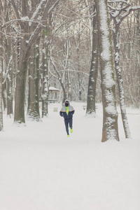 男人在充满雪的公园里锻炼跳跃和跑步。