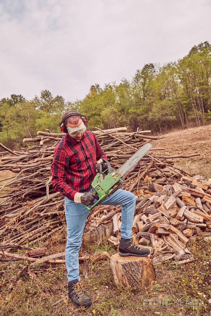 伐木工人拿着电锯和一堆锯木