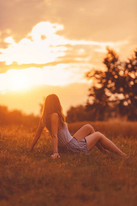 在金色的日落时间在草地上享受的女孩。