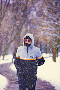 男人在下雪的公园和寒冷的天气慢跑。