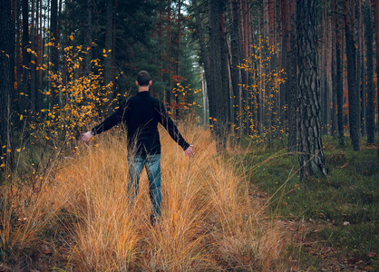 年轻人站在秋天的森林里，手举彩色照片