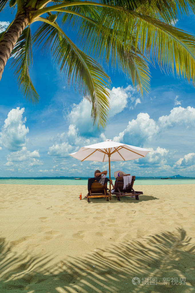 一对夫妇坐在泰国热带海滩上放松的浪漫场景