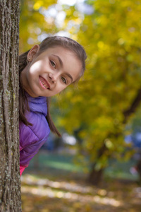 微笑的女孩望着秋天公园的树