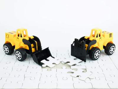 白色背景上有拼图的玩具推土机和叉车。