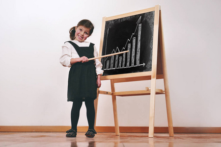 一个穿着教师服装的快乐小女孩在一个小黑板前上了一堂经济学团队合作数学课 理念 教育学校业务和热爱学习 照片 正版商用图片1449xn 摄图新视界
