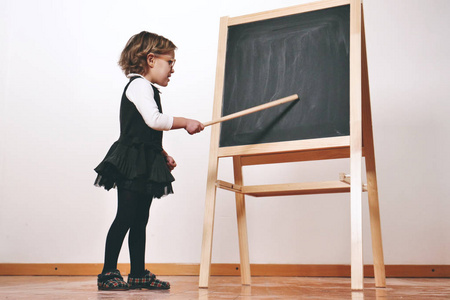 一个穿着教师服装的快乐小女孩在一个小黑板前上了一堂经济学团队合作数学课 理念 教育学校业务和热爱学习 照片 正版商用图片1449xn 摄图新视界