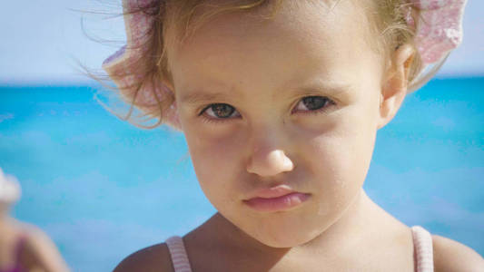 一个美丽的小女孩在海上玩得很开心的肖像，可爱的海水蓝色的微笑背景。 概念儿童童年暑期自由儿童女儿宝宝微笑。