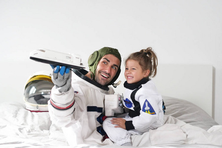 浪漫和家庭的时刻，爸爸和女儿玩宇宙飞船，都打扮成宇航员，并在这个独特的时刻快乐。 概念热爱家庭游戏。