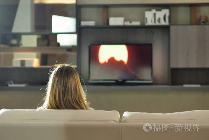 一个女人在新房子的沙发上看电视看电影概念休闲放松电视