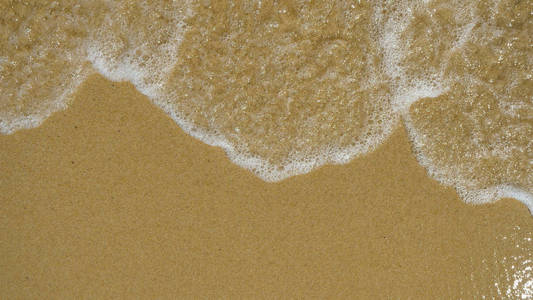 棕色沙子上的波浪被波浪背景冲走。 概念休息大海，海滩，海岸，海浪的声音自由。