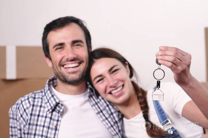 微笑的白种人夫妇拿着新房子的钥匙，看着镜头
