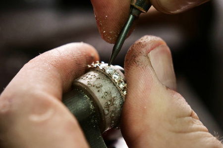 s hand making a gold or silver ring or a diamond using goldsmith