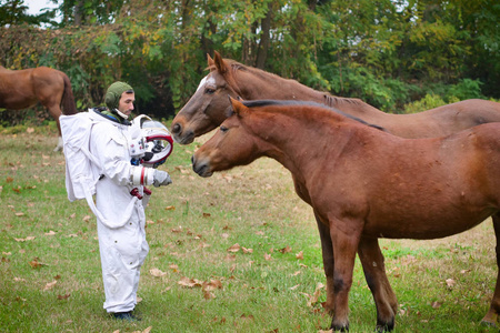一位宇航员刚刚从太空降落在新星球上，抚摸着两匹漂亮的马，作为对动物爱的象征。 概念动物喜欢激情宇航员新世界和新冒险。