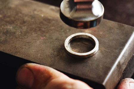 s hand making a gold or silver ring or a diamond using goldsmith