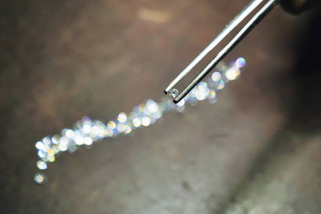 接近一个金匠的手，他用专业的镊子检查钻石，他将用于生产手工豪华珠宝。 概念传统豪华珠宝。