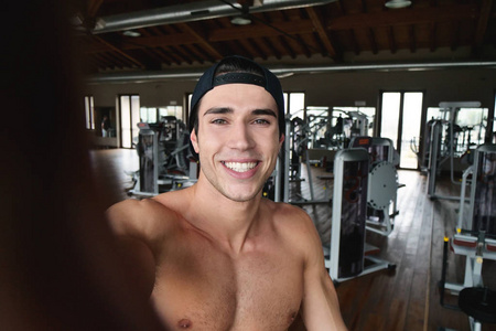 微笑的白种人肌肉男在健身房自拍照片