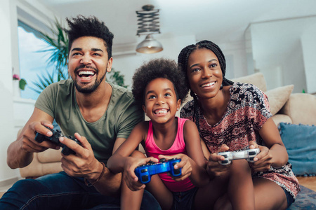 微笑的家人坐在沙发上一起玩电子游戏