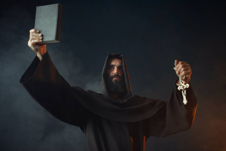 中世纪僧侣站在火中,手里拿着书,黑色的背景秘密仪式.