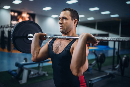 强壮的男性举重运动员在健身房里做举重。 举重锻炼举重训练运动员在体育俱乐部里举重
