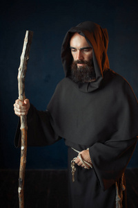 天主教修士中世纪僧侣穿着黑色长袍,戴着头巾,靠的是棍子宗教.