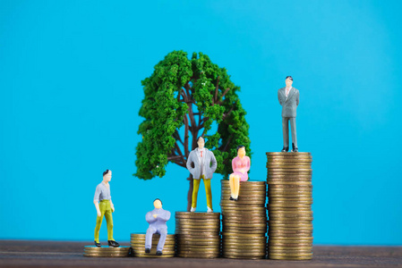 图微型商人或小人物投资者和上班族秘书站在硬币堆上，用小树装饰，为金钱和金融商业的成功理念。