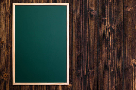 空的绿色黑板，木桌上的木框，顶部的视图与复制空间，以增加文本和信息。