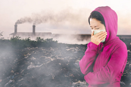 女人穿着粉红色的冬天衣服，戴着面具对着鼻子，在空气污染的背景下，以感冒和流感的健康理念。