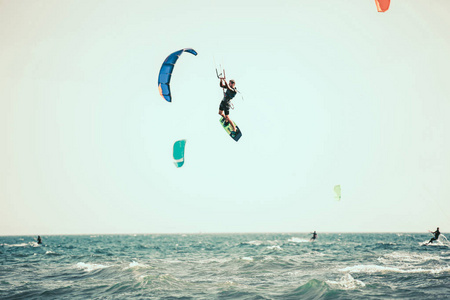 专业的Kiter在一个美丽的背景上制造了困难的技巧。Kitesurfing风筝板动作照片人在海浪中很快就走了