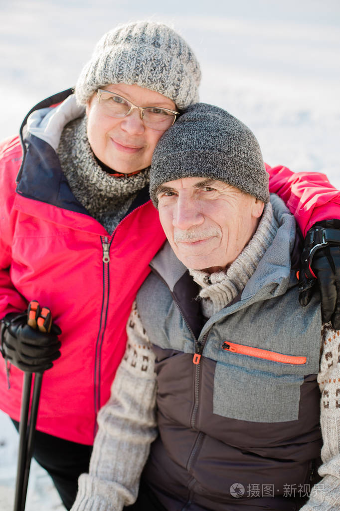 在冬季公园里和北欧的步行杆坐在一起成熟的女人和老人在户外休息健康