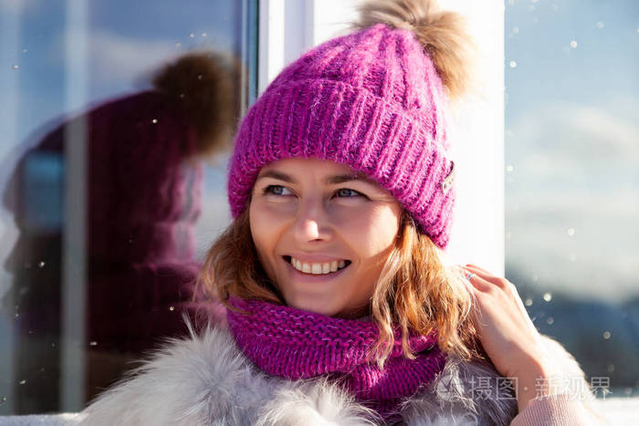 戴着粉红色的针织帽,温暖的双手,微笑,远离视线,在寒冷的冬天散步