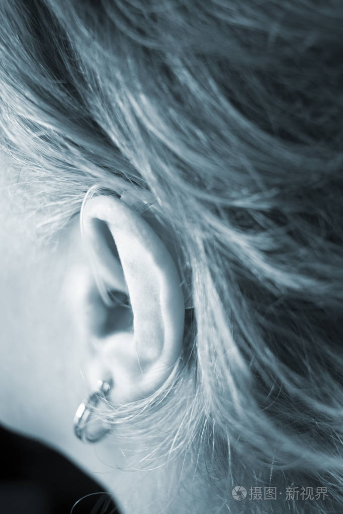 聋人女士她的耳朵里有现代技术数字助听器