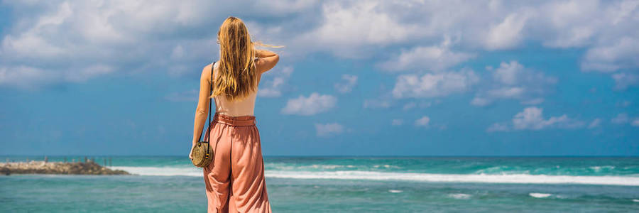 年轻的女性旅行者放松在令人惊叹的梅拉斯蒂海滩与绿松石水巴厘岛印度尼西亚岛。