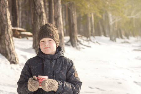 微笑的十几岁的男孩穿着温暖的衣服，炎热的冬天喝着接近的肖像，冬天在户外白雪。 家庭冬季周末或假日冬季娱乐活动和健康的休闲理念。